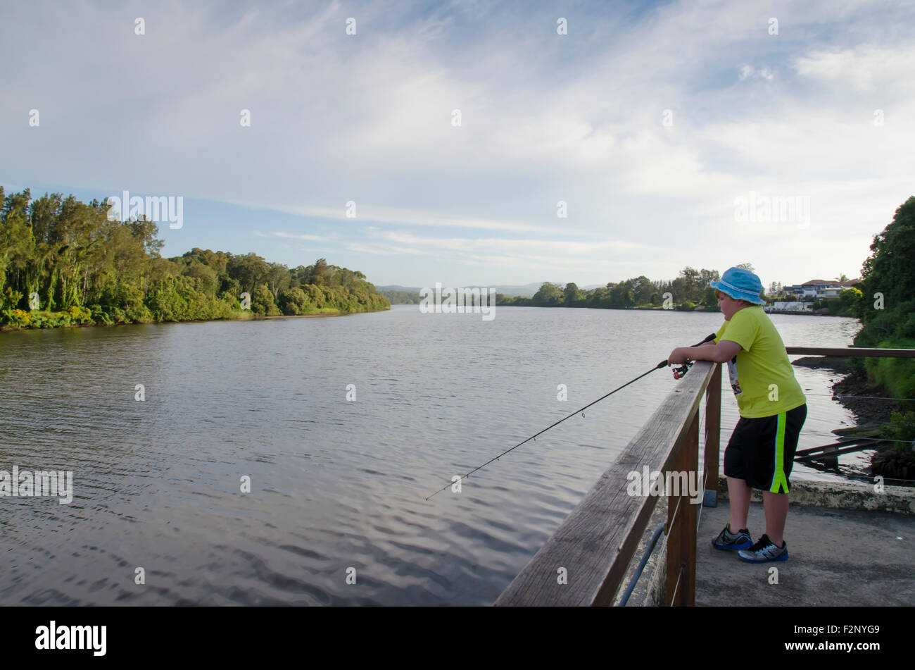 Un ragazzo giovane che pesca accanto ad un fiume nel NSW, Australia Foto Stock