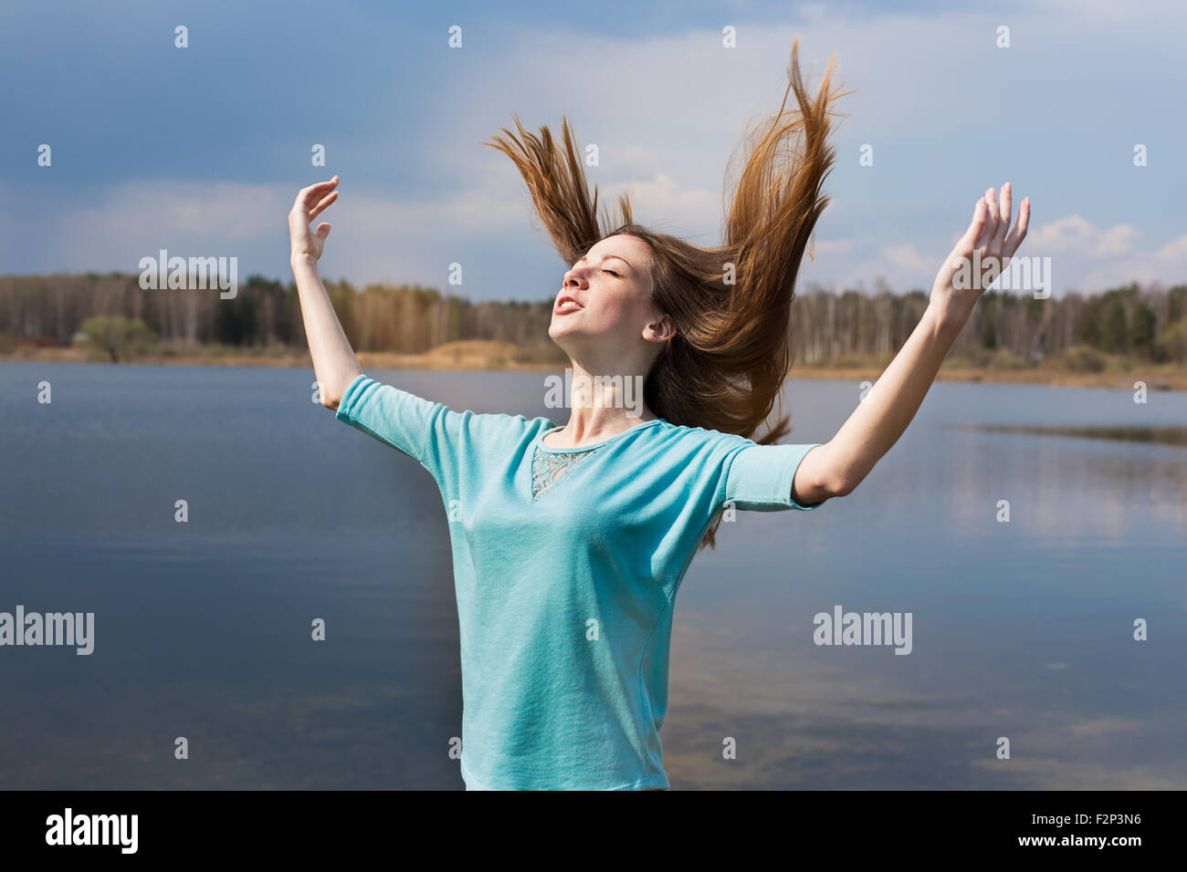 Freckled felice ragazza con le braccia tese a sorridere al sole e chiudendo gli occhi Foto Stock