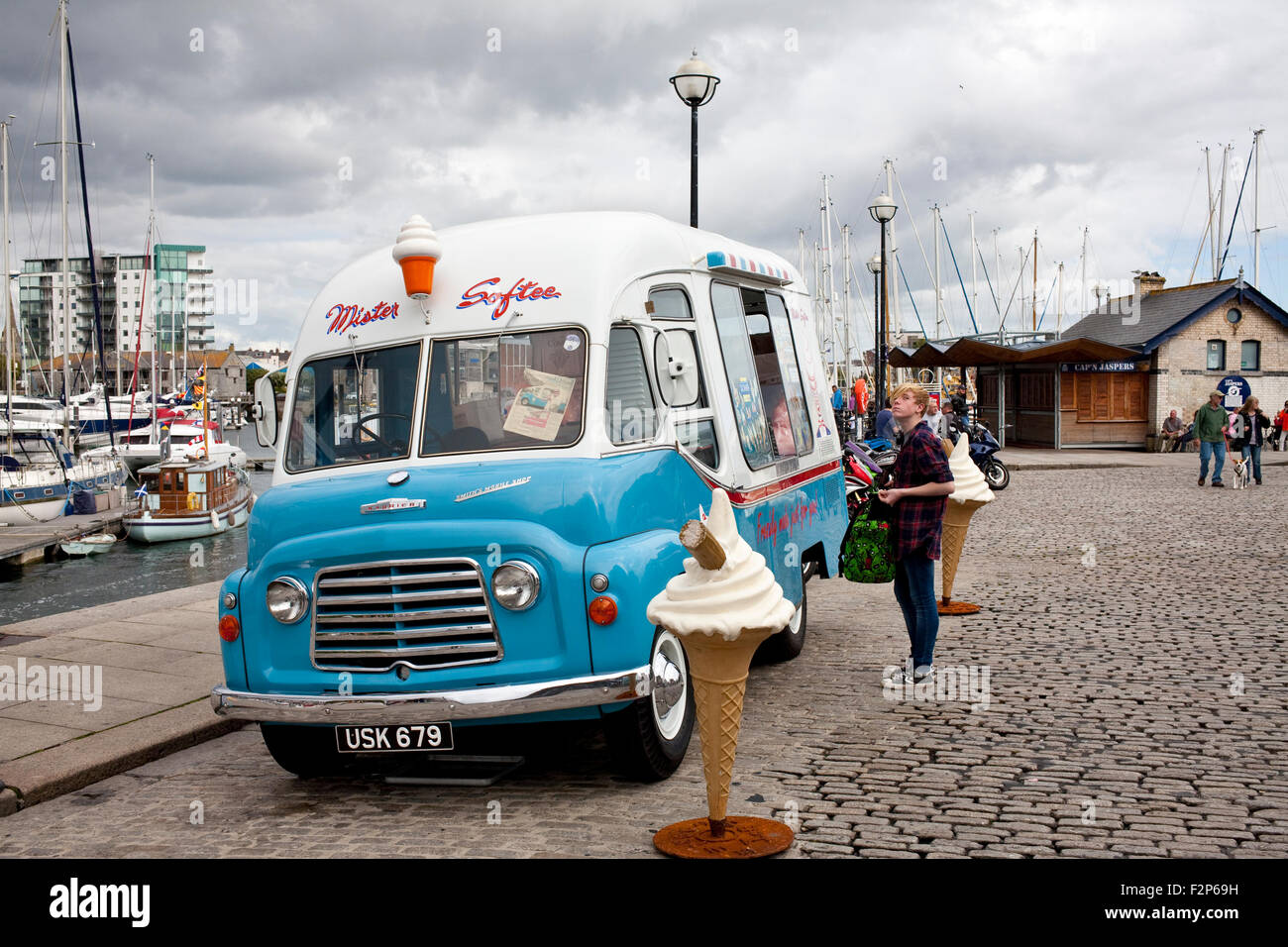 Acquisto maschio da un Mister softee 1960,s Commer Karrier ice-cream van sul lastricato della banchina di Sutton Harbour, Plymouth Foto Stock