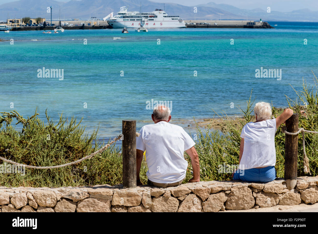 Due persone anziane che guarda al mare alla nave di grandi dimensioni. Correlejo, Fuerteventura Isole Canarie Spagna Foto Stock