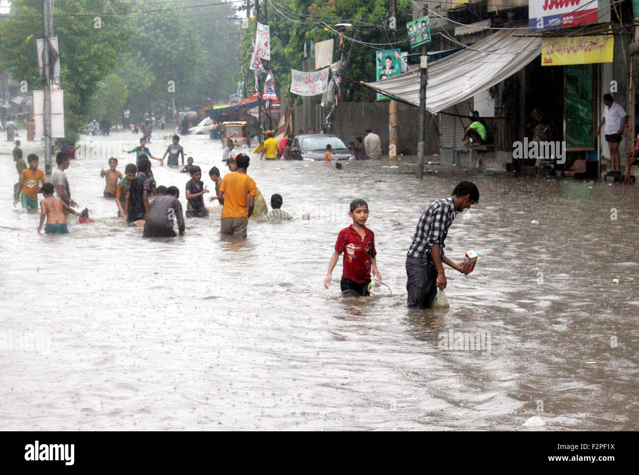 I bambini giocano in accumulo di acqua di pioggia durante la pioggia pesante a Lahore Martedì, 22 settembre 2015. Il capoluogo della provincia del Punjab sperimentato forti precipitazioni martedì portando ad una ripartizione di potenza in diverse zone della città. Varie aree pianeggianti, compresi Lakshmi Chowk, Dharampur, Wasanpur e altri sono stati inondati dopo il diluvio. Foto Stock