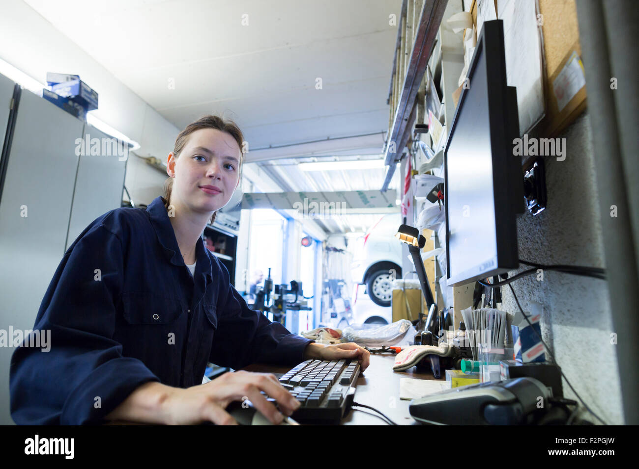Giovane donna che lavorano nel garage di Riparazione, scrittura di report di controllo Foto Stock