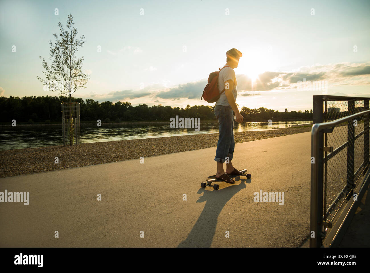 Uomo in piedi su skateboard nel crepuscolo della sera Foto Stock