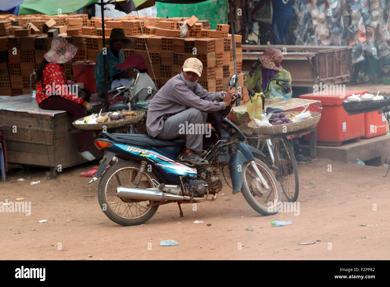 Scena di strada uomo seduto moto mercato polverosi Foto Stock