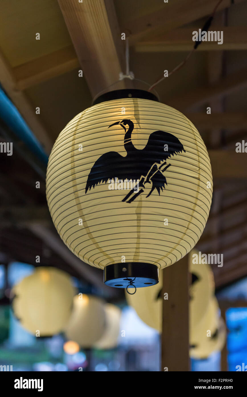 Una lanterna di carta con un logo di cormorani su di esso pendente dal tetto di una imbarcazione turistica Foto Stock