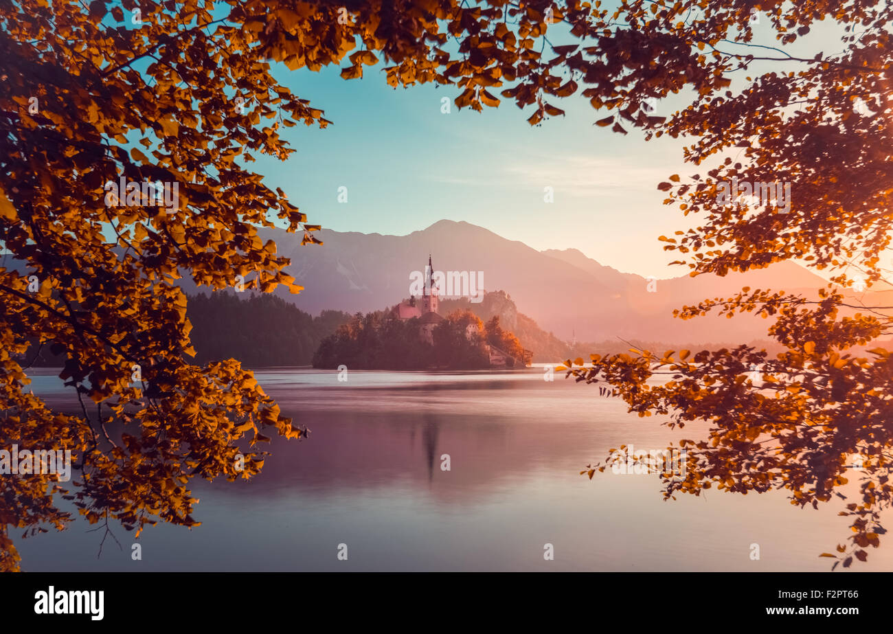 La piccola isola con la Chiesa cattolica nel lago di Bled, Slovenia all'alba con il castello e le montagne sullo sfondo. Filtro d'autunno. Tr Foto Stock