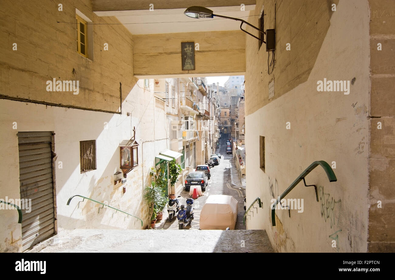 Città in scena per le strade de La Valletta con architettura e macchine parcheggiate al di sotto di una scala Foto Stock