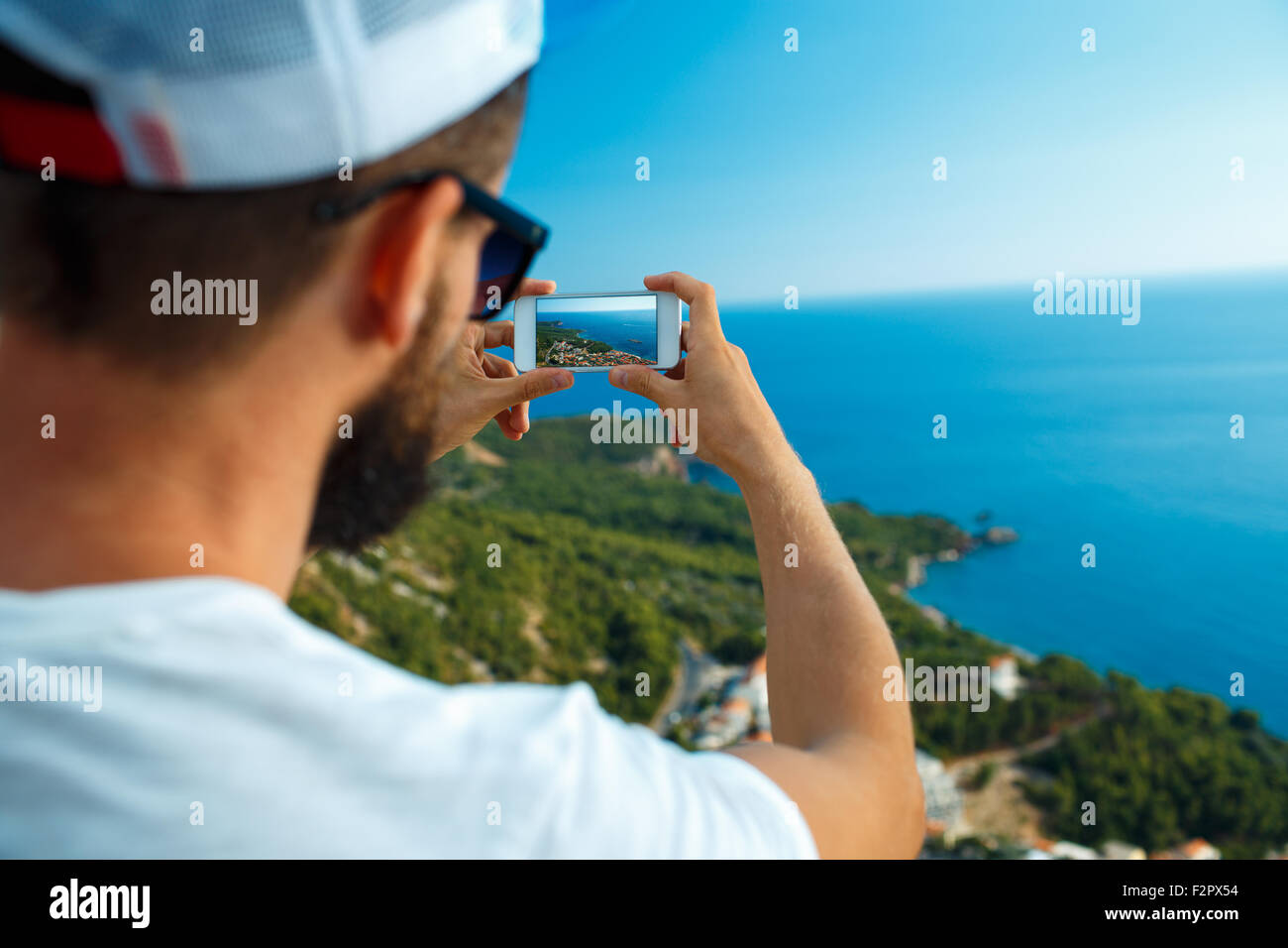 L uomo rende le foto da uno smartphone sullo sfondo del mare, mare adriatico, Montenegro, Balcani Foto Stock