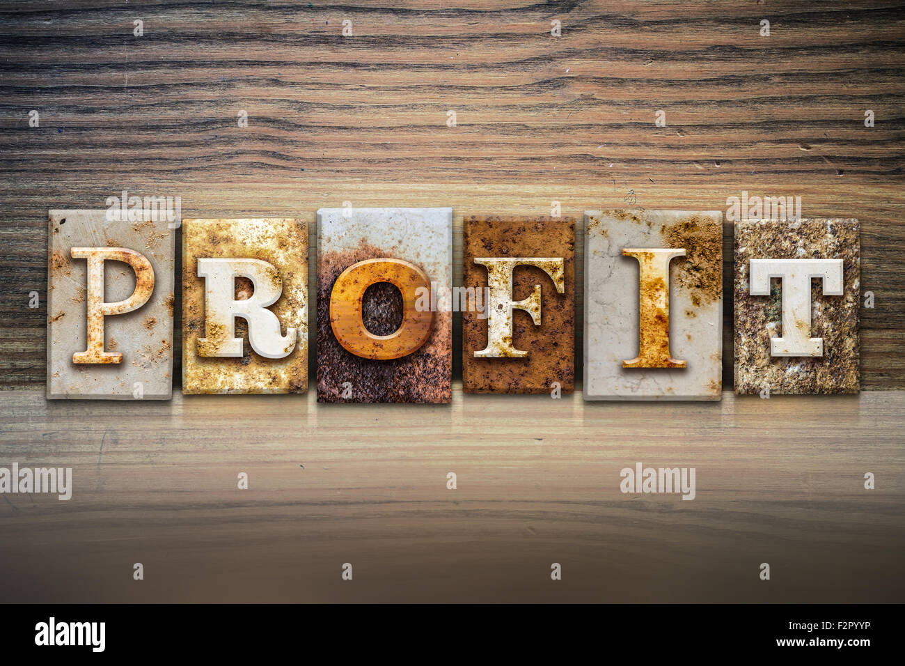 La parola 'profitto' scritto in metallo arrugginito rilievografia tipo seduto su un listello di legno dello sfondo. Foto Stock