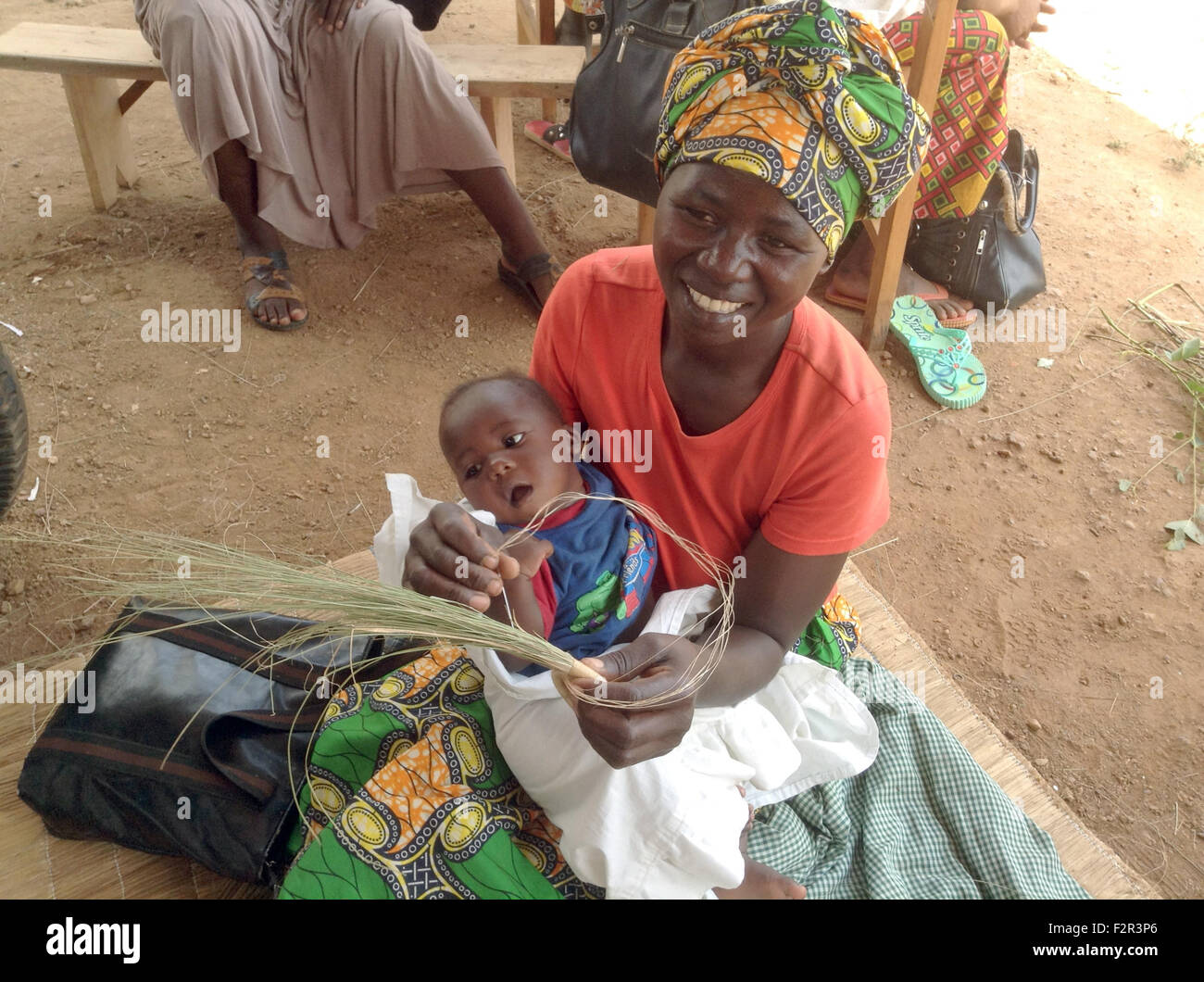 Mayange, Ruanda. 6 Mar, 2015. Weaver Agnes Mukamtwari tiene i suoi 5 mese-vecchio figlio Daniel durante la tessitura di un cesto di paglia al Millennium Village di Mayange, Ruanda, 6 marzo 2015. Con l'aiuto del millennio progetto villaggi, Mukamtwari era in grado di pagare i propri debiti e ora anche di assicurazione sanitaria. Foto: JESKO JOHANNSEN/DPA/Alamy Live News Foto Stock