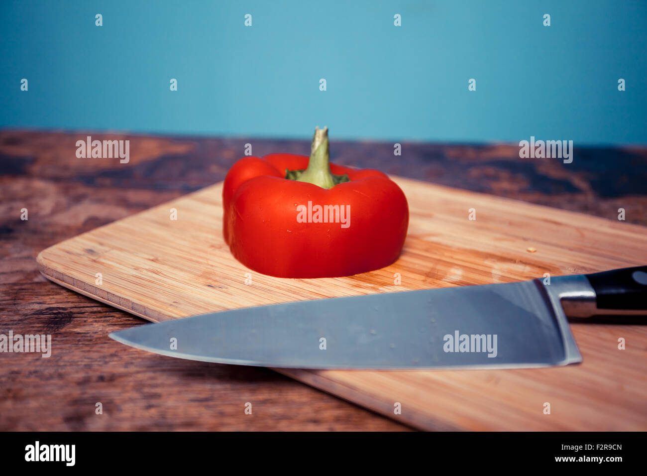 Coltello e tagliare il peperone rosso sul tagliere Foto Stock