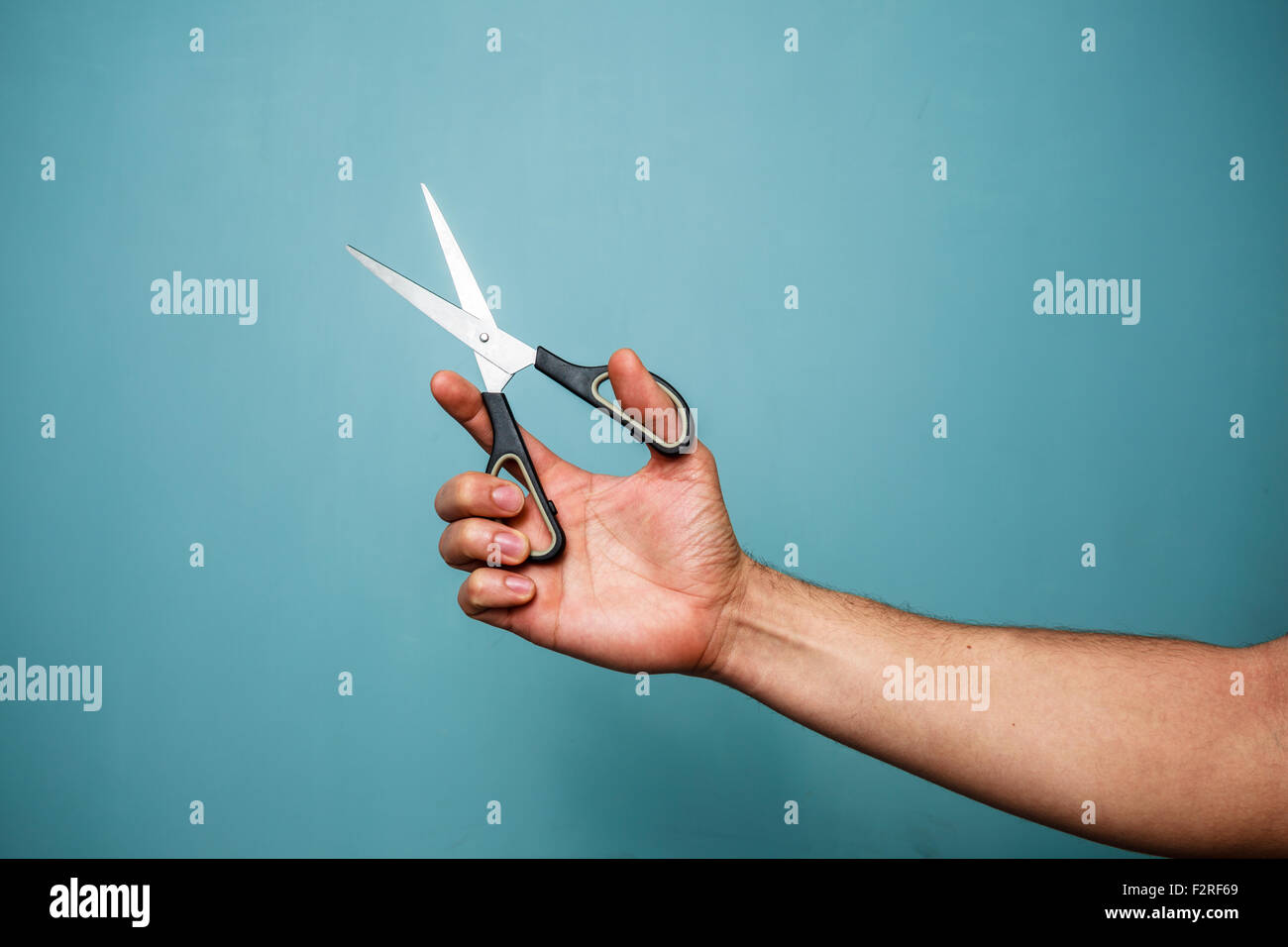 Mano d'uomo è in possesso di un paio di forbici aperte Foto Stock