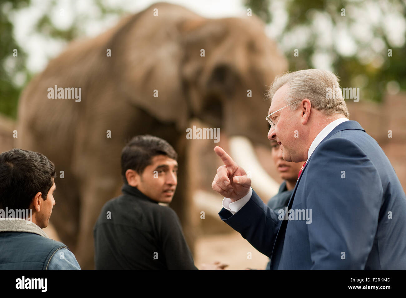 Un Senatore di Berlino Frank Henkel (r, CDU) stand con refugeee bambini dall'Afghanistan nella libera compresa recinto degli elefanti a Berlino, Germania, 23 Septemeber 2015. I bambini sono ospitati come parte di un'iniziativa 'Kinderpatenschaft der Hauptstadtzoos' (lt: bambino sponsorizzazione della città principale giardini zoologici) con il sostegno di associazione Tierpark Berlin e lo Zoo di Berlino e gli studenti provenienti da George Orwell scuola. Lo scopo è quello di finanziare i bambini rifugiati le visite allo zoo e anche per raccogliere le donazioni per le loro famiglie. Patrono della raccolta fondi è Berlino di interni il senatore Frank Henkel. PHOT Foto Stock