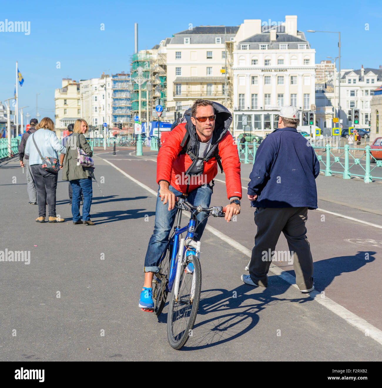 Ciclista che si aggira intorno a persone che camminano su una pista ciclabile a Brighton, East Sussex, Inghilterra, Regno Unito. Foto Stock