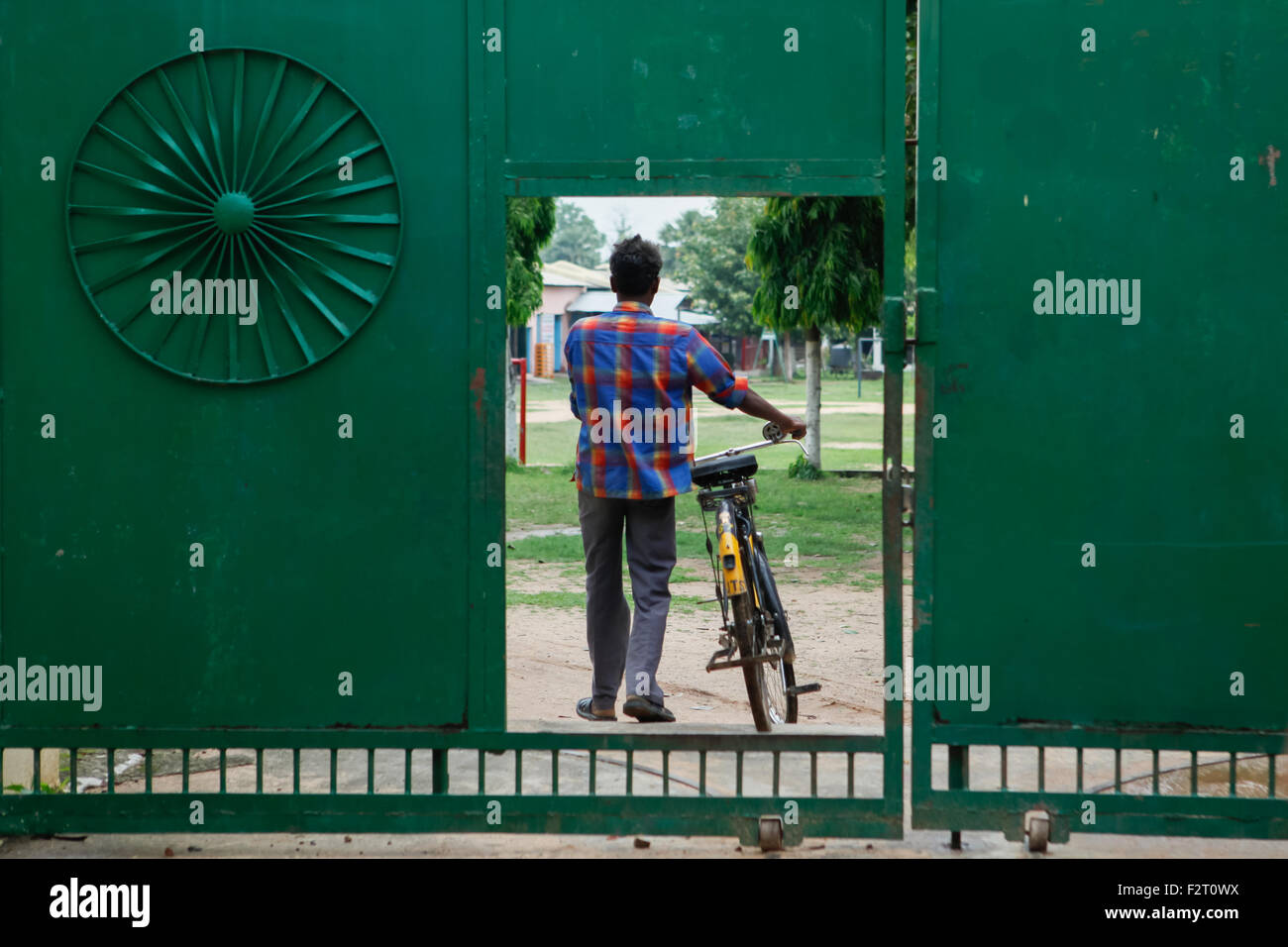 Un uomo trasporta la bicicletta mentre entra nel complesso dell'Accademia di Sujata, che è una scuola libera e un dormitorio per i bambini rurali a Dungeshwari, Bihar, India. Foto Stock