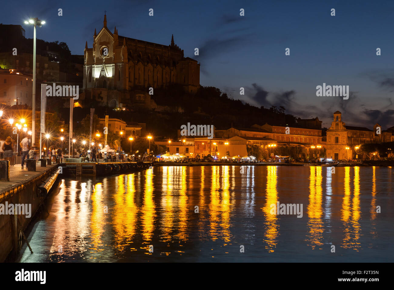 Paesaggio urbano in notturna con le luci riflesse in acqua di mare. Città di Gaeta, Italia Foto Stock