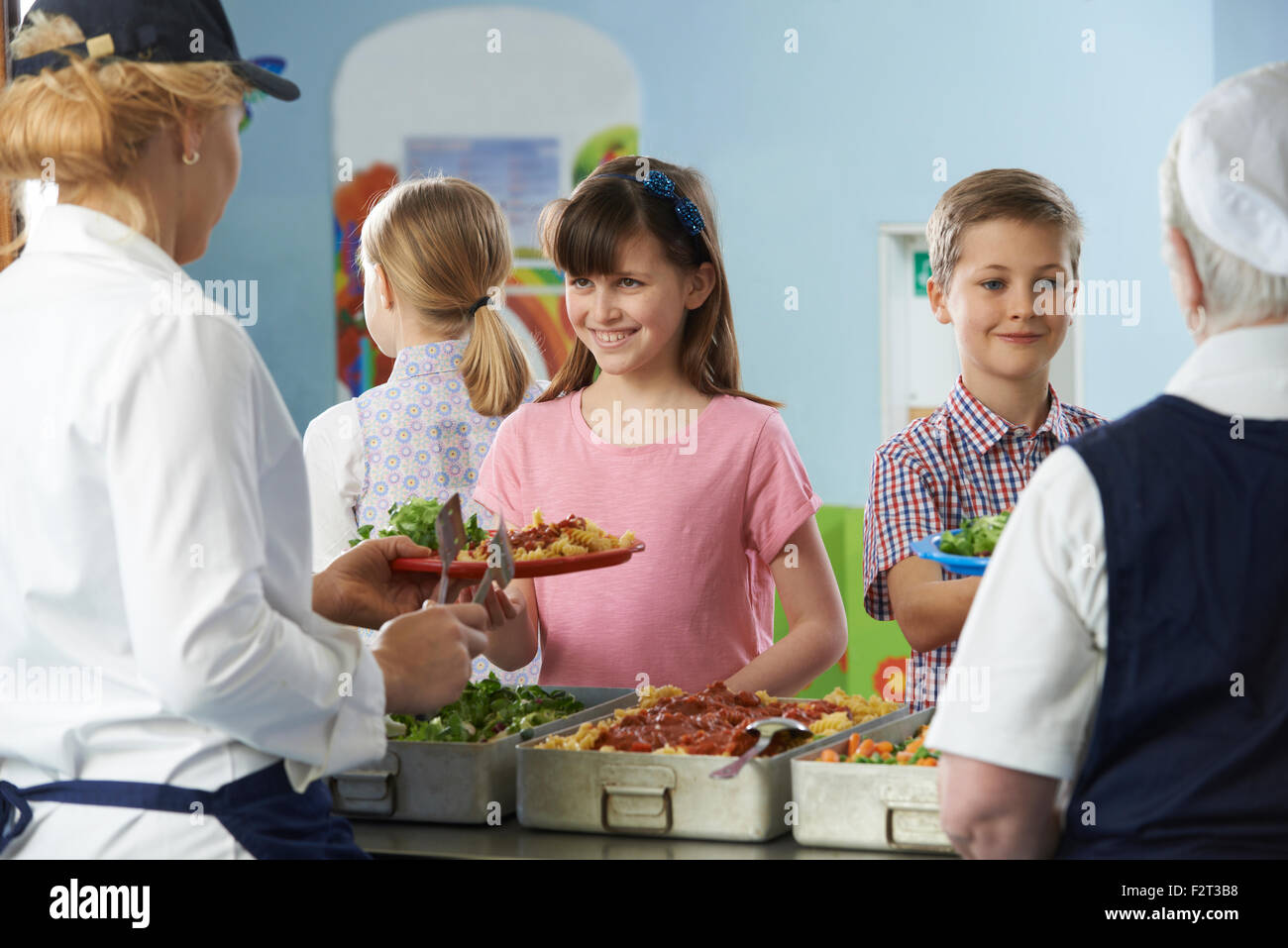 Gli alunni di essere servito con un sano pranzo in mensa scolastica Foto Stock