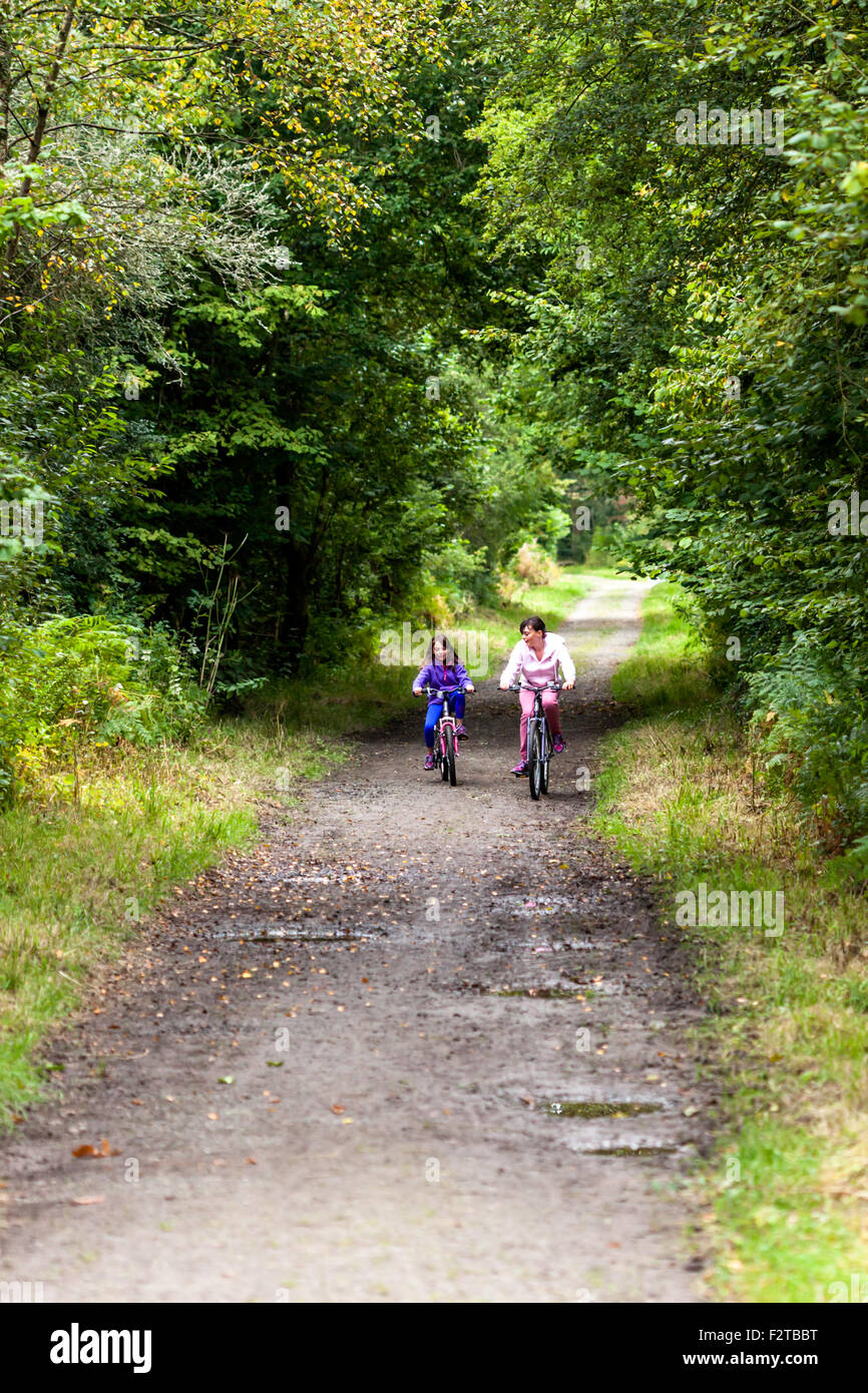 2 ragazze in sella moto lungo una vecchia linea ferroviaria ora convertito in un percorso di ciclo Foto Stock