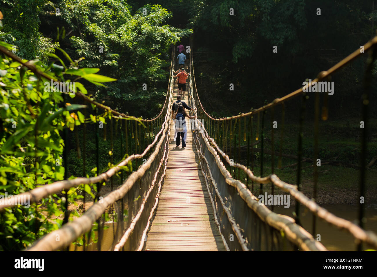 Ponte di Legno attraversare il fiume con i turisti nella giungla. Foto Stock