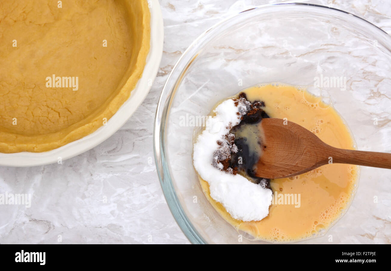 Agitazione zucchero in uovo sbattuto per la torta di zucca riempimento, pasta vuota accanto a caso Foto Stock