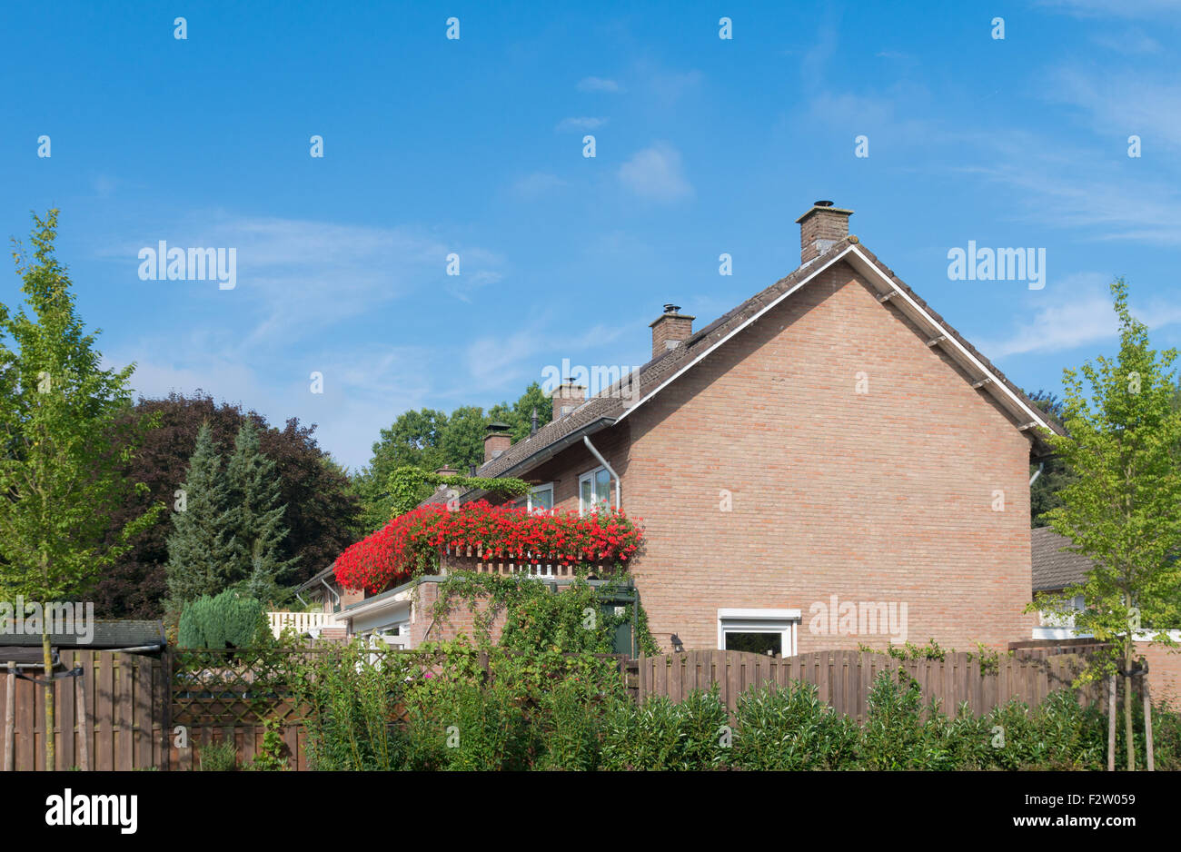 Casa semplice con lage balcone pieno con fioriture di gerani rossi fiori Foto Stock
