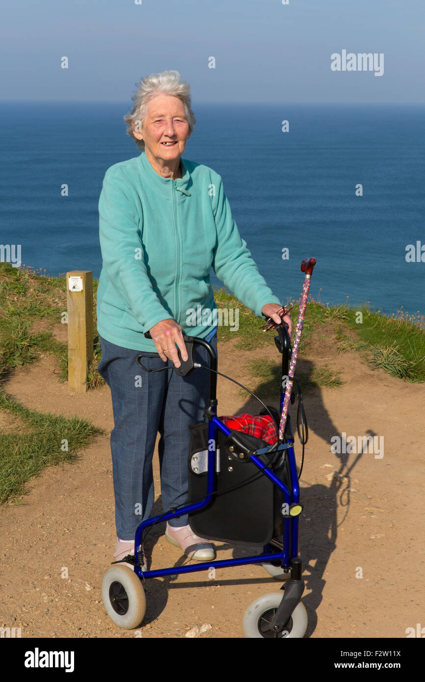 Active vecchio pensionato femmina con tre ruote carrello aiuto per la mobilità da coste Foto Stock