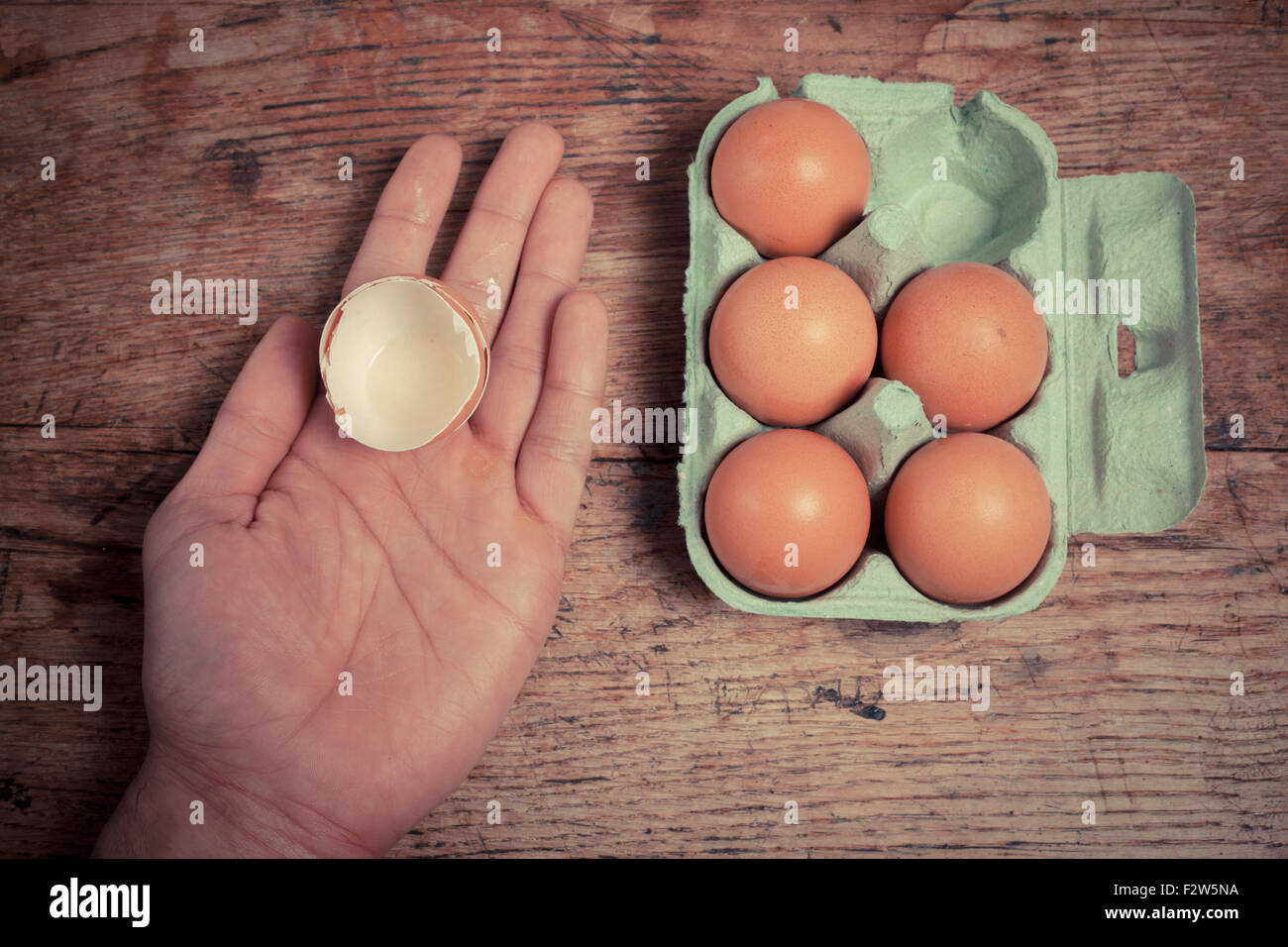 Un uomo è in possesso di un guscio delle uova in mano a una tabella Foto Stock