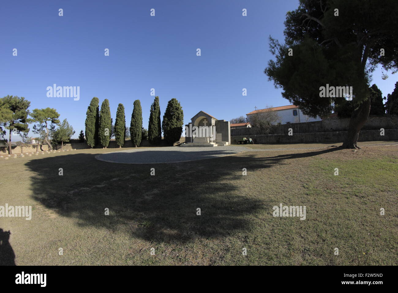 Cipressi e la grande croce cove lontano offuscato da un albero.vista dell'architettura CWGC Portianos cimitero. Lemnos, GR Foto Stock