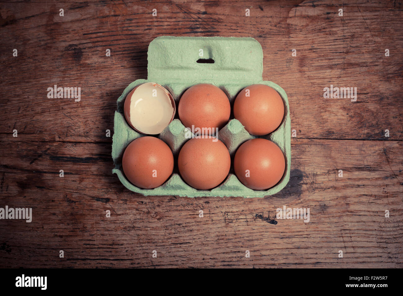 Cinque uova e un guscio in un vassoio di cartone su una tavola di legno Foto Stock
