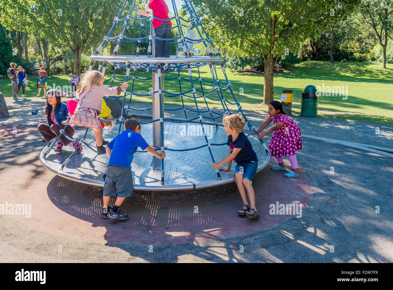Bambini che giocano sulla rotatoria nel parco giochi Foto Stock