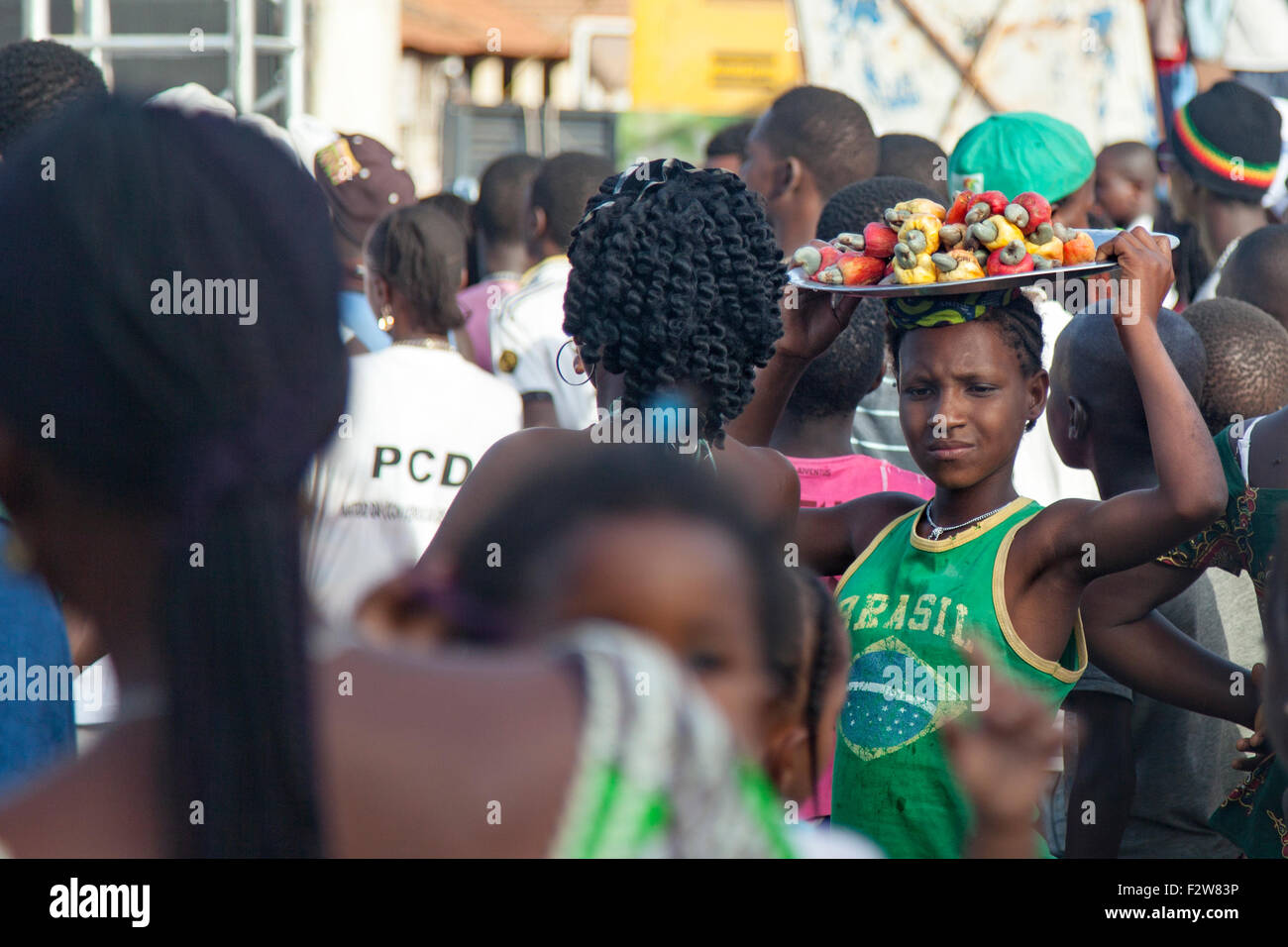 Ragazza africana la vendita di acagiù nel mezzo di una folla Foto Stock