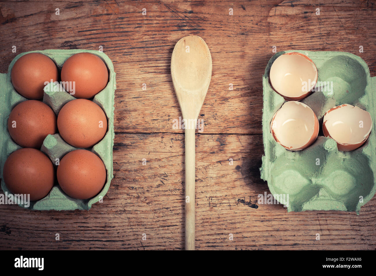 Cucchiaio di legno tra due vassoi di uova e gusci sul tavolo Foto Stock