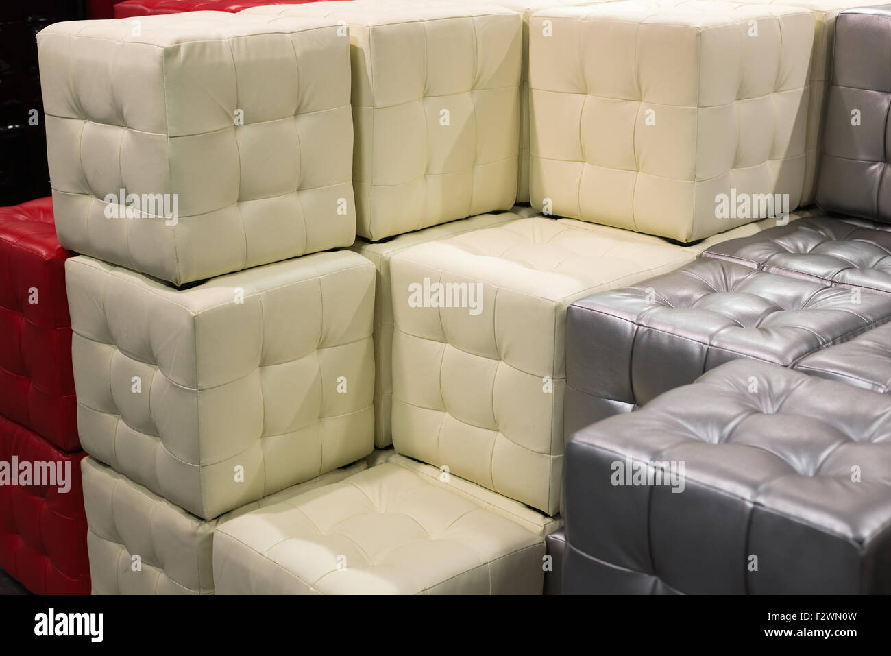 Molti footstools in pelle di diversi colori in pila Foto Stock