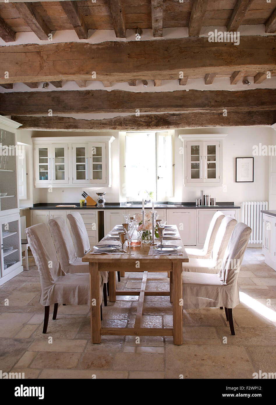 Bianco copre allentato su sedie in legno semplice tabella impostata per il pranzo nel paese italiano sala da pranzo Foto Stock