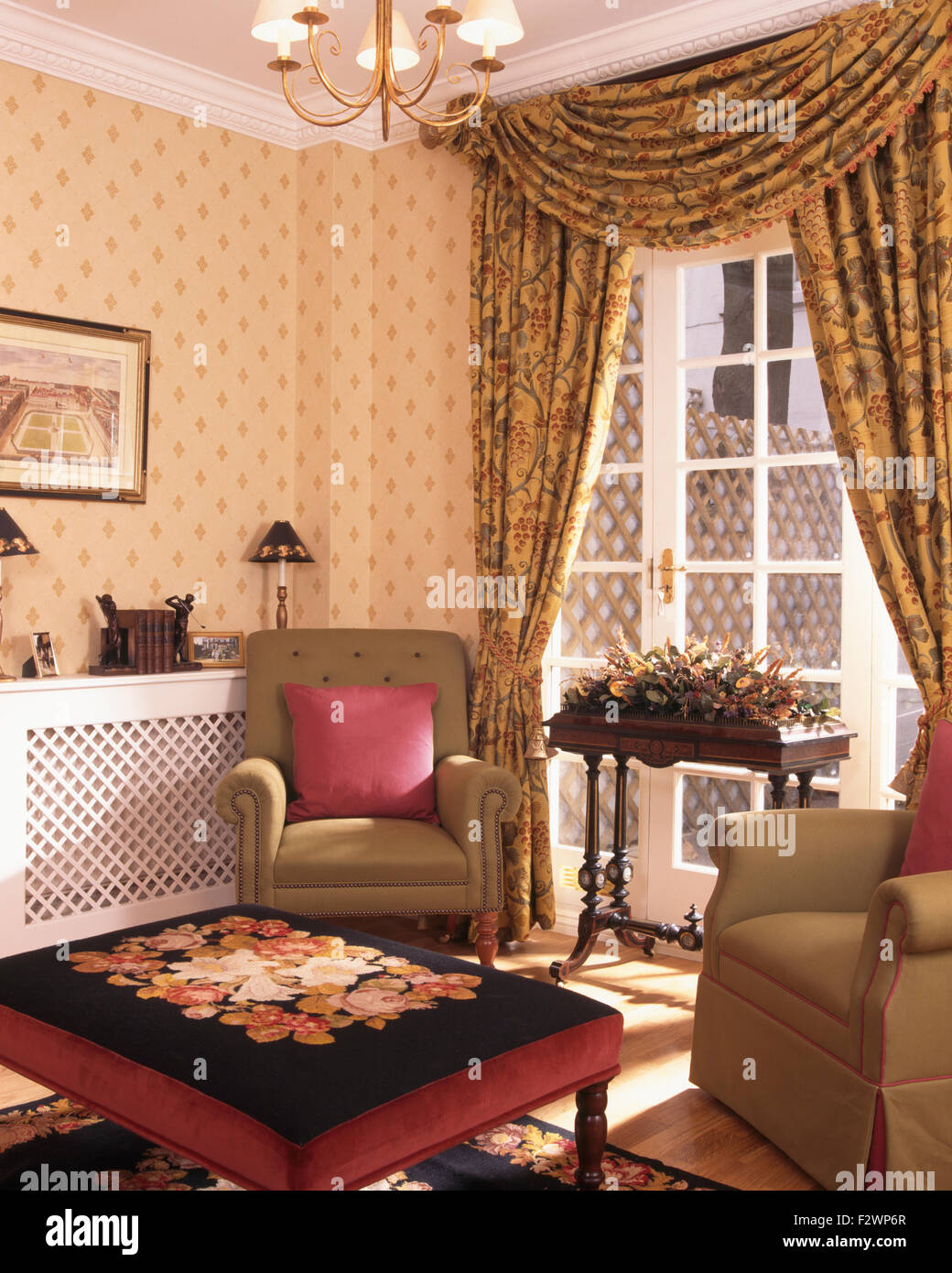Arazzo sgabello coperte e tende swagged negli anni novanta soggiorno con carta da parati con motivi geometrici e poltrone di colore beige Foto Stock