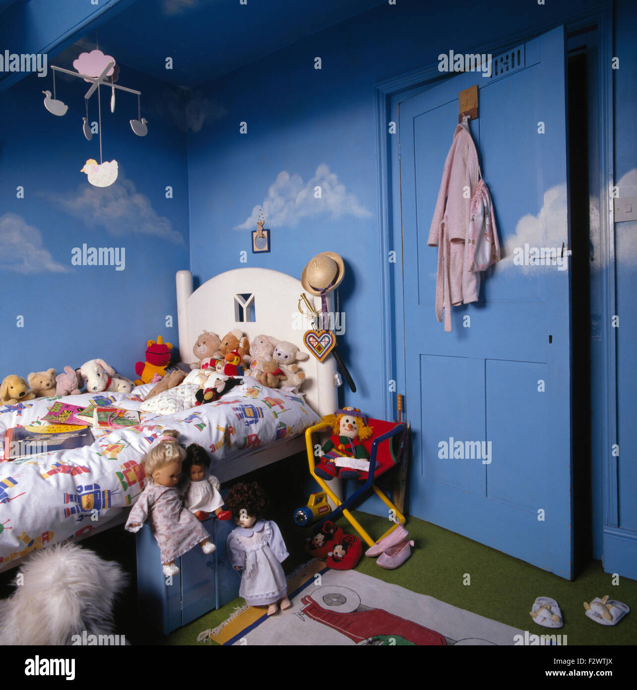 Verniciato bianco impilati a letto con giocattoli e bambole in bambini degli anni novanta blu camera da letto con un mobile in legno Foto Stock
