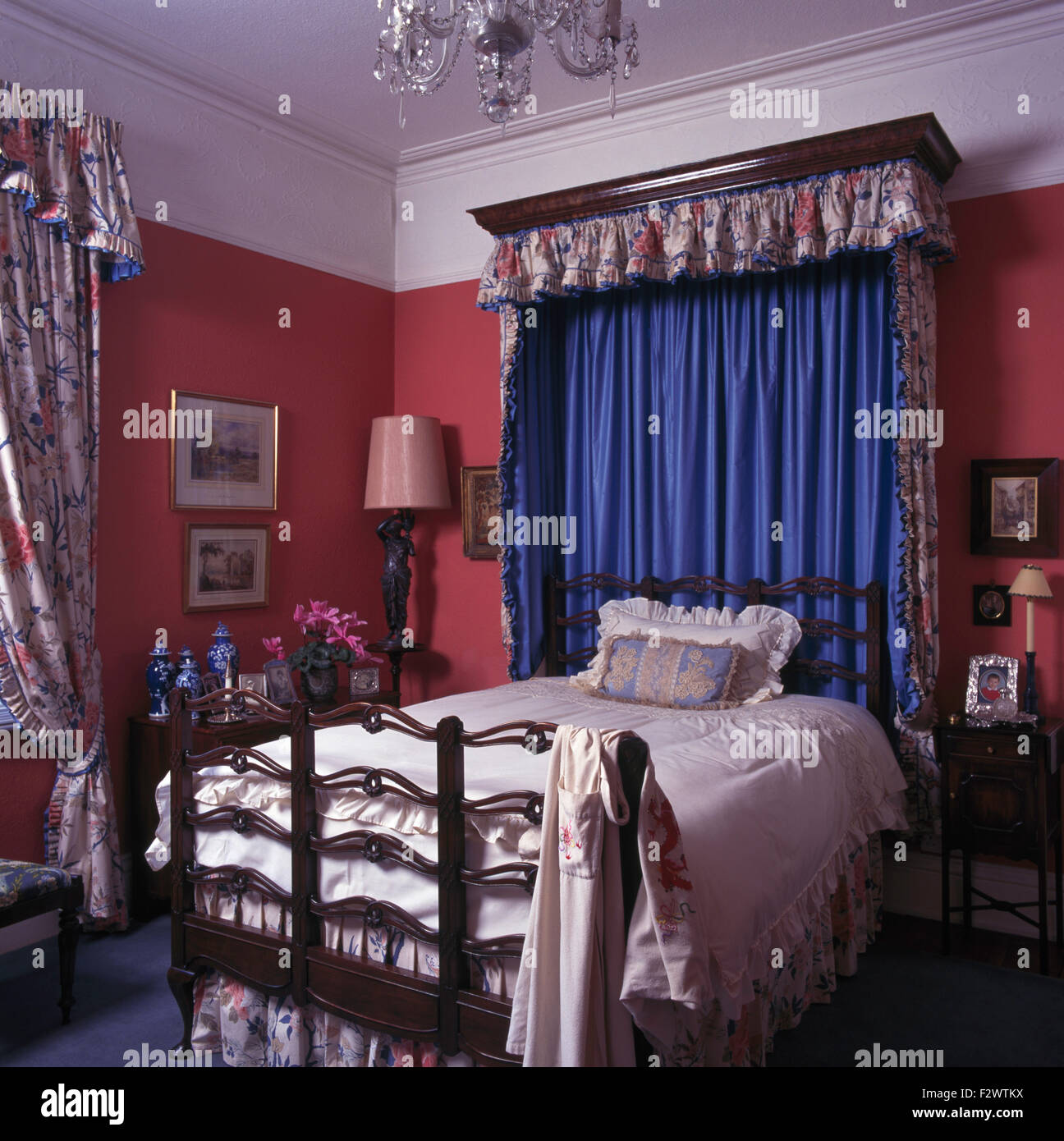 Tettoia con tende blu e floreale mantovane sul letto in rosso degli anni novanta camera da letto Foto Stock