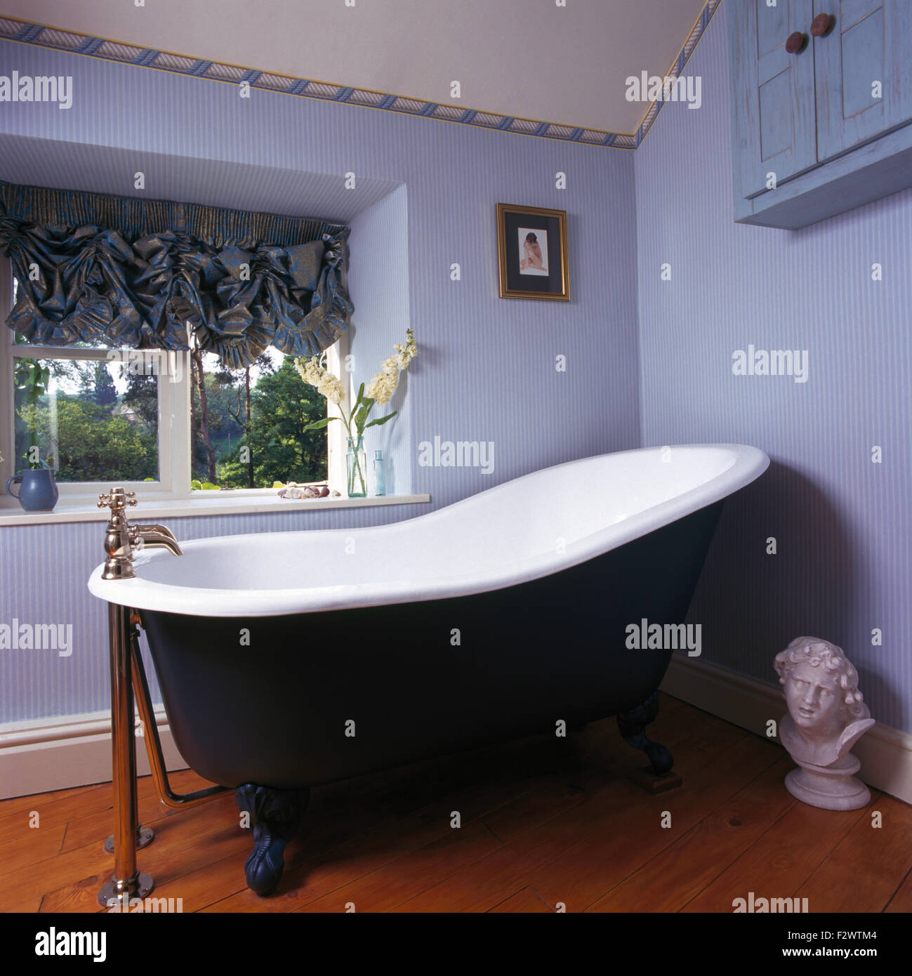 Roll top bagno in novanta bagno blu con carta da parati a strisce e un festone cieco Foto Stock