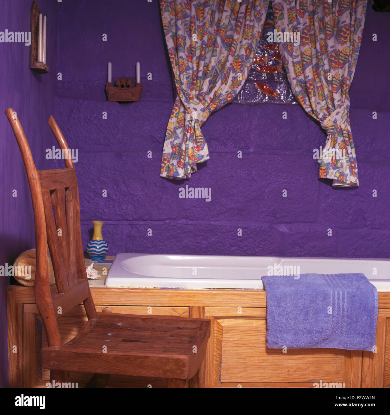 Tende a motivi geometrici su piccola finestra al di sopra di vasca da bagno con pannelli di pino in piccole viola degli anni novanta il bagno Foto Stock