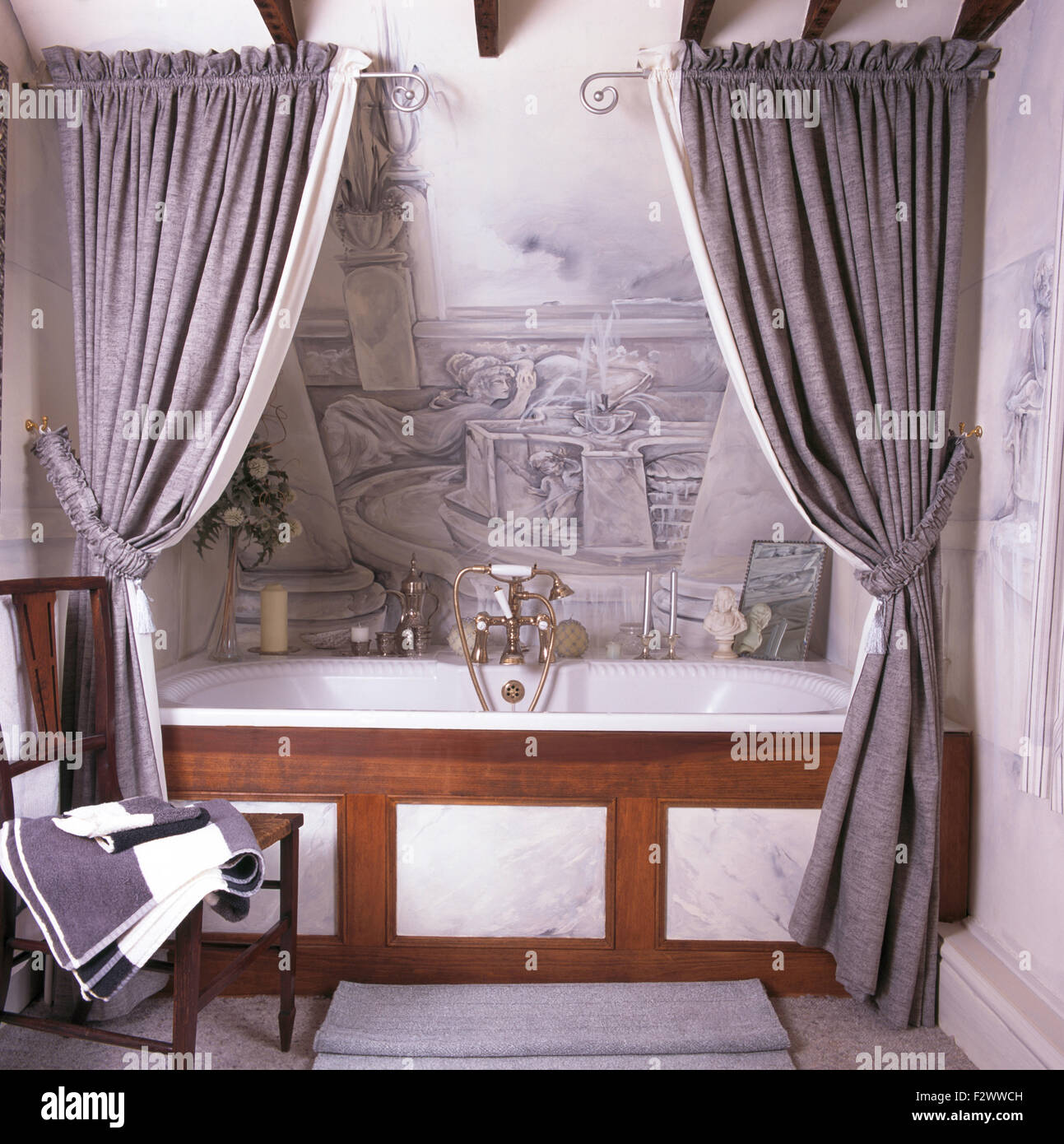 Tende di colore grigio sulla vasca da bagno in novanta bagno con  trompe-l'oeil murale dipinto sulla parete sopra il bagno Foto stock - Alamy