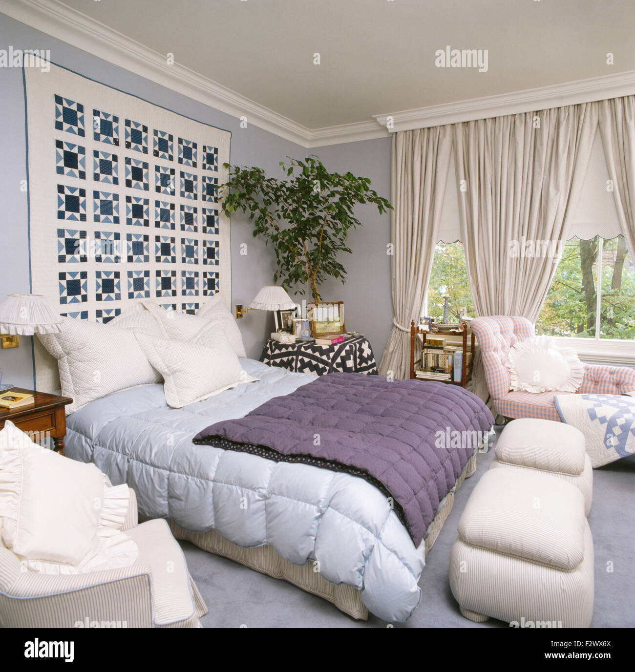 Mosaico sulla parete sopra il letto con blu pallido e viola le trapunte in ottanta townhouse camera da letto Foto Stock