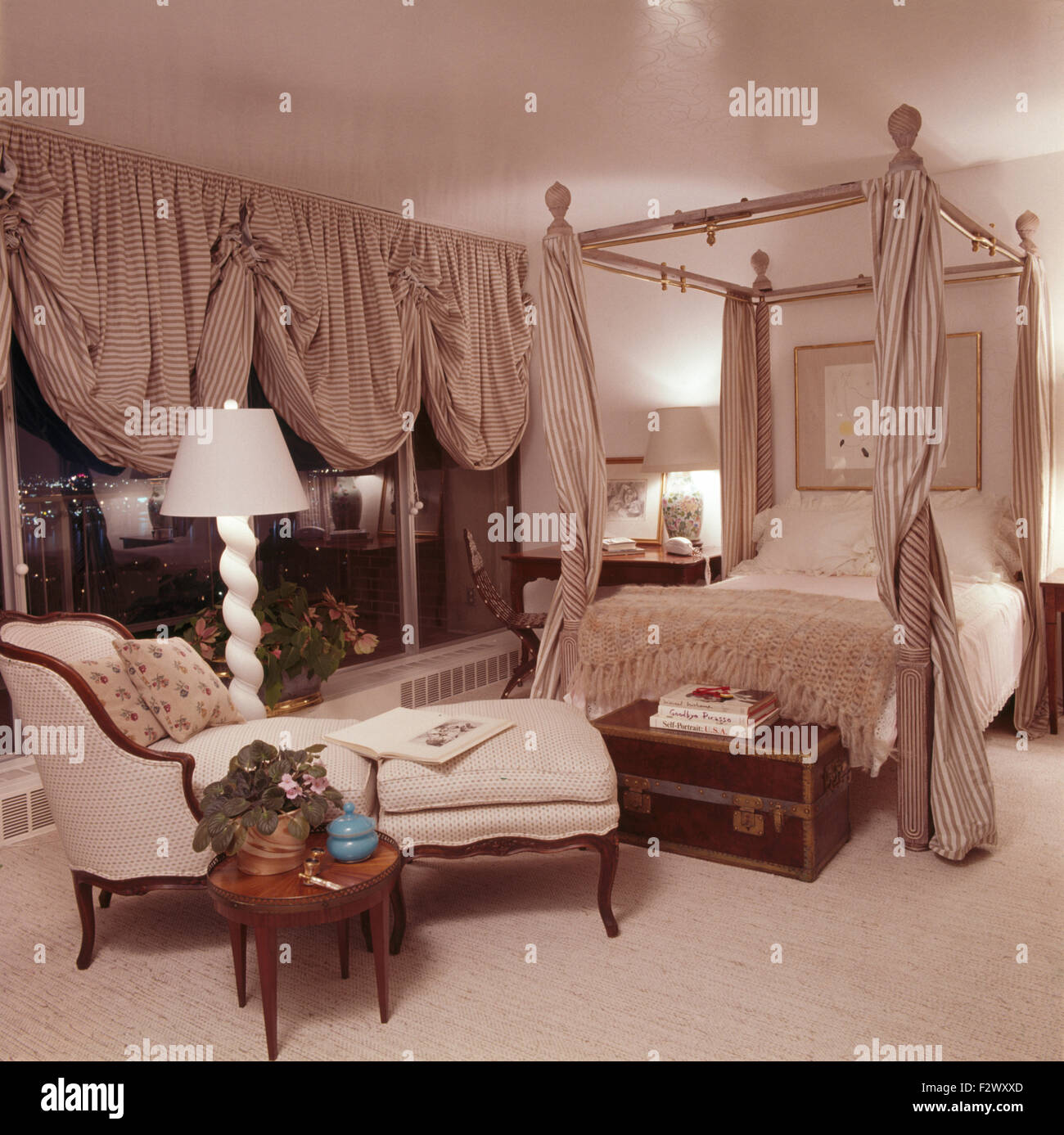 Striped festone persiane delle finestre in opulento camera da letto degli anni ottanta con abbinamento di tende a strisce su un letto a baldacchino Foto Stock