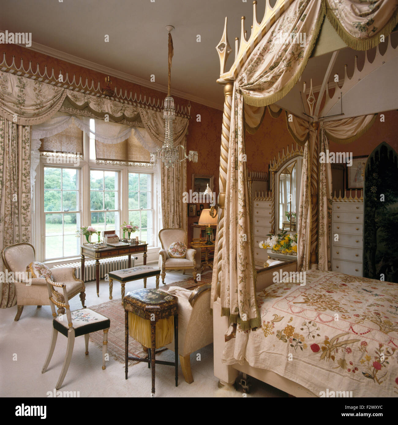 Swagged tende su finestra in camera da letto opulenta con drappi di seta su un stile gotico letto a baldacchino Foto Stock