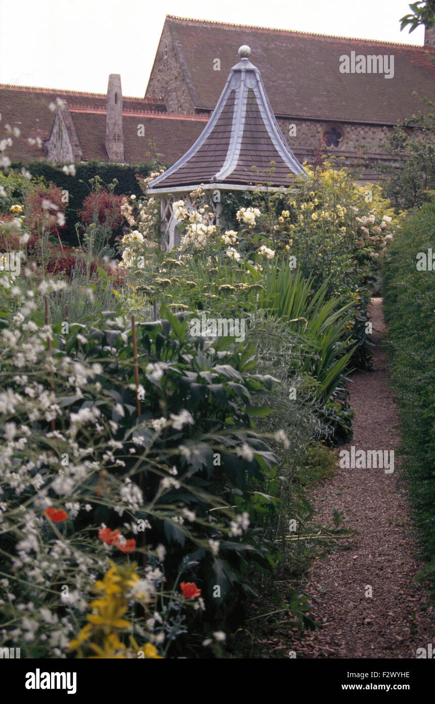 Crambe bianco e rose in border accanto al sentiero di ghiaia a summerhouse esagonale con un tetto di tegole Foto Stock