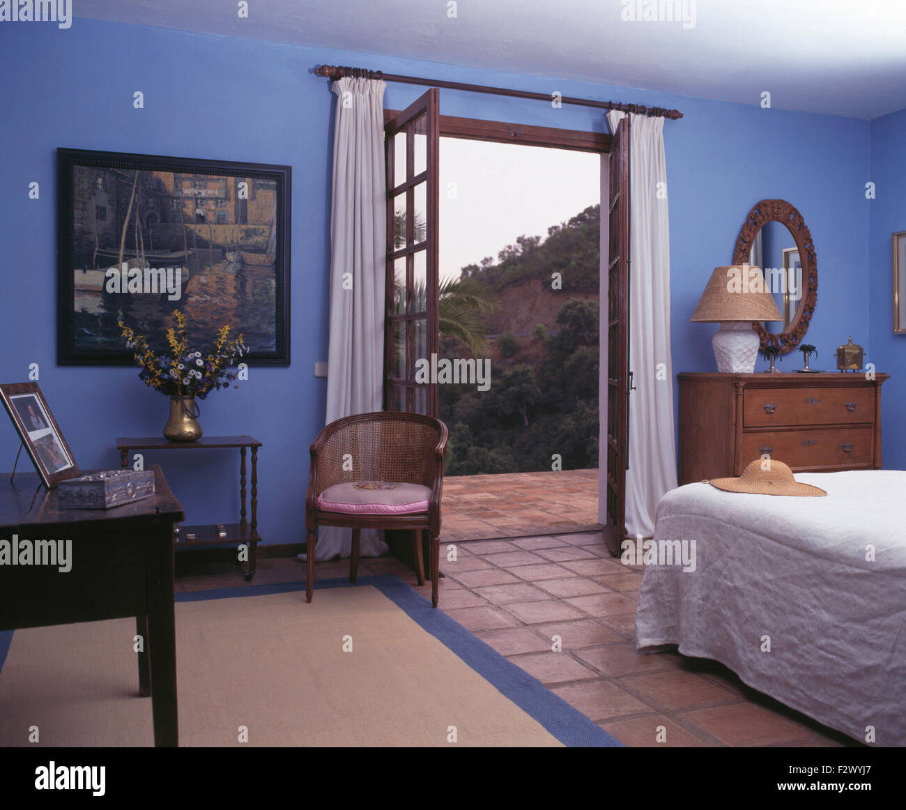 Blu paese spagnolo camera da letto con tende bianche sulle finestre Francesi alla terrazza Foto Stock
