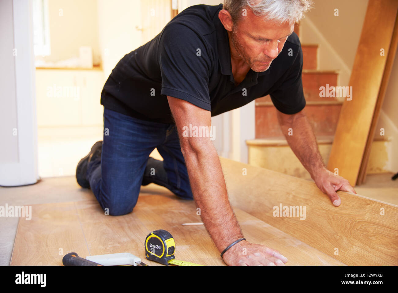 Uomo di posa del pannello in legno pavimentazione durante una ristrutturazione della casa Foto Stock