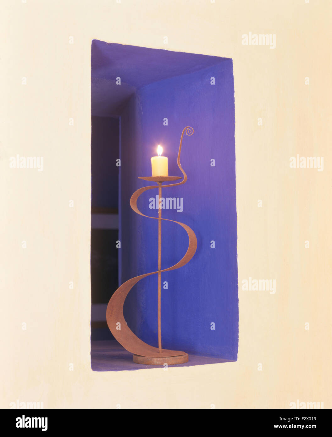 Close-up di un metallo candelabro con una candela accesa in una alcova blu Foto Stock