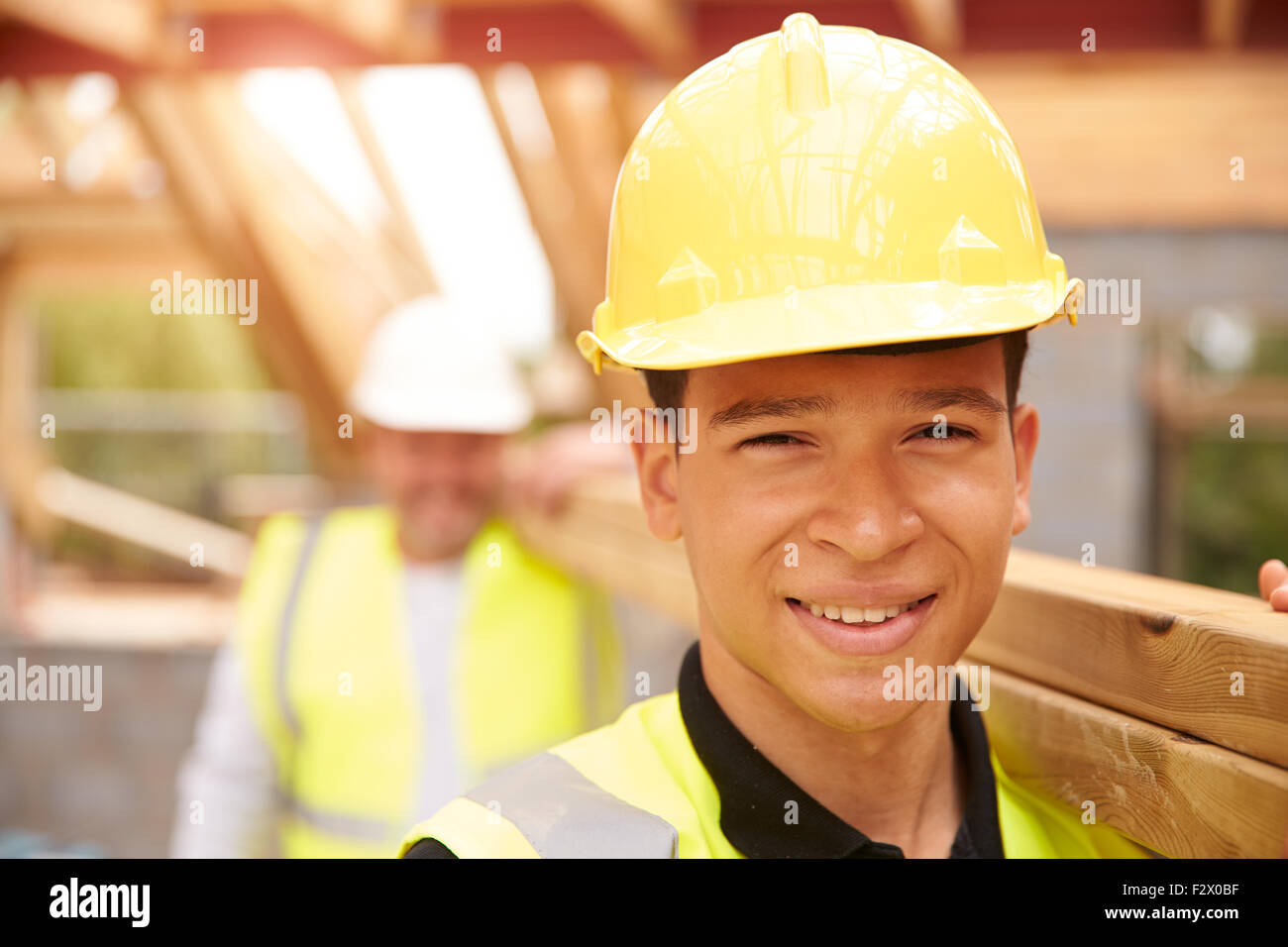 Ritratto di Builder e Apprendista trasportare il legno sul sito Foto Stock