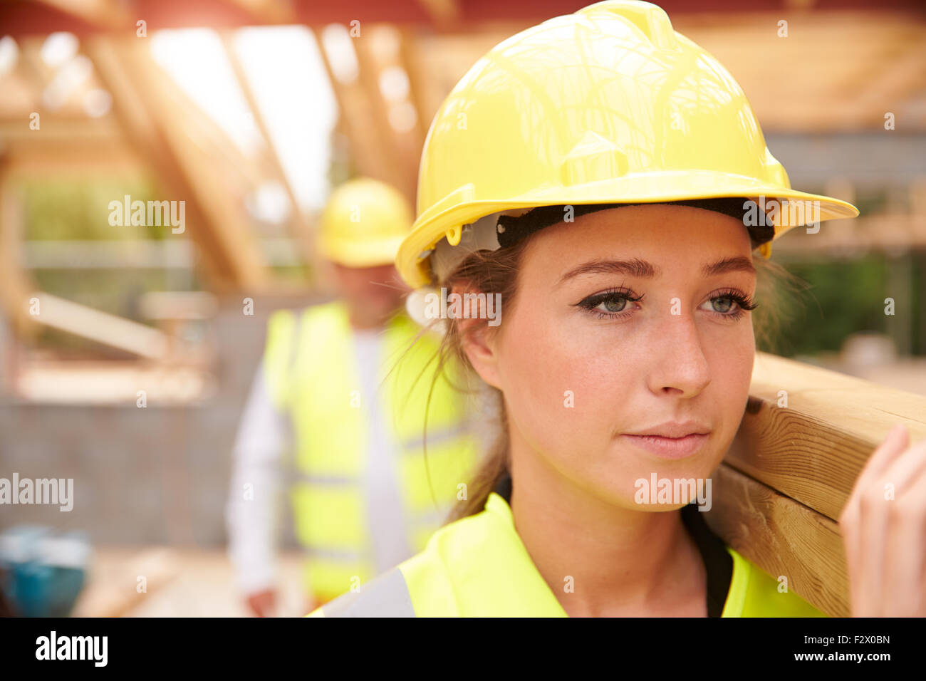 Builder e Apprendista femmina trasportare il legno sul sito Foto Stock
