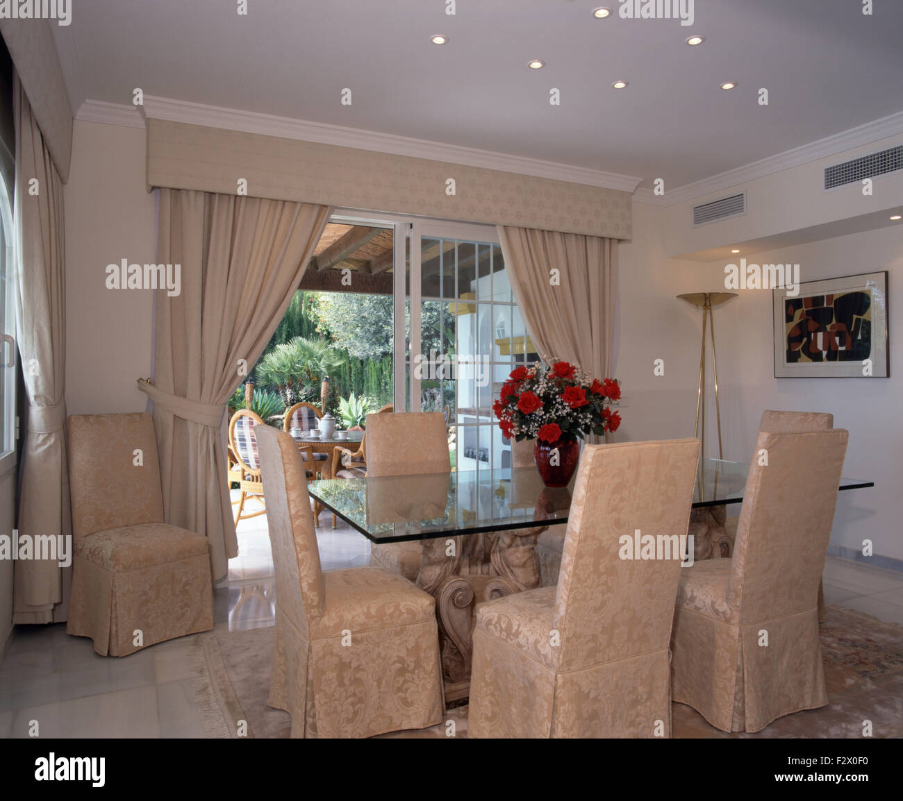 Damasco copre allentato su sedie a ripiano in vetro tavolo in spagnolo sala da pranzo Foto Stock